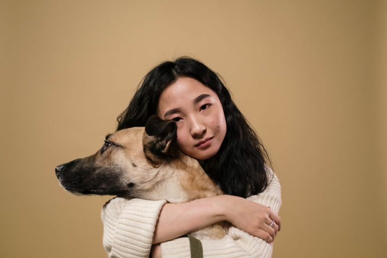 Mujer abrazando a su perro frente a un fondo beige