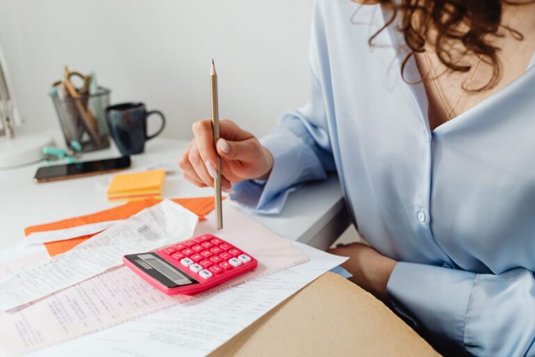 Mujer revisa cuentas con una calculadora en su escritorio