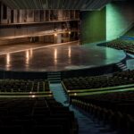 Interior de un teatro con filas de sillas frente al escenario