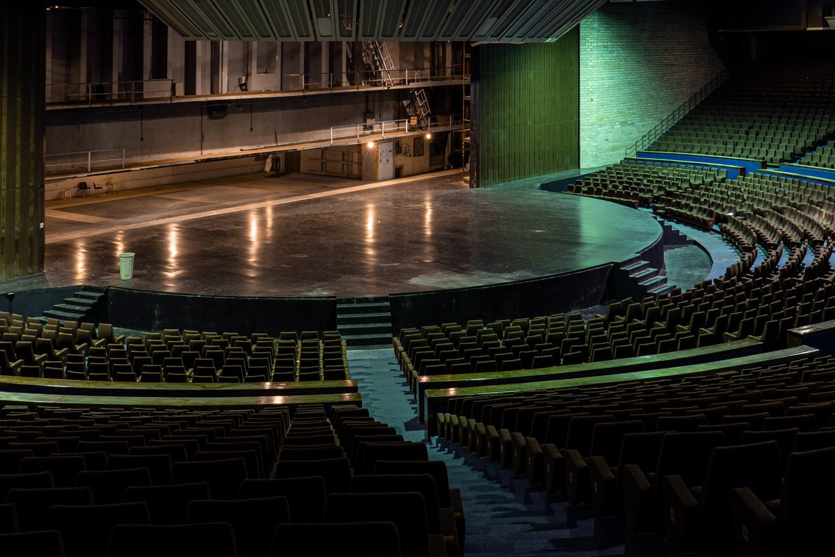 Interior de un teatro con filas de sillas frente al escenario