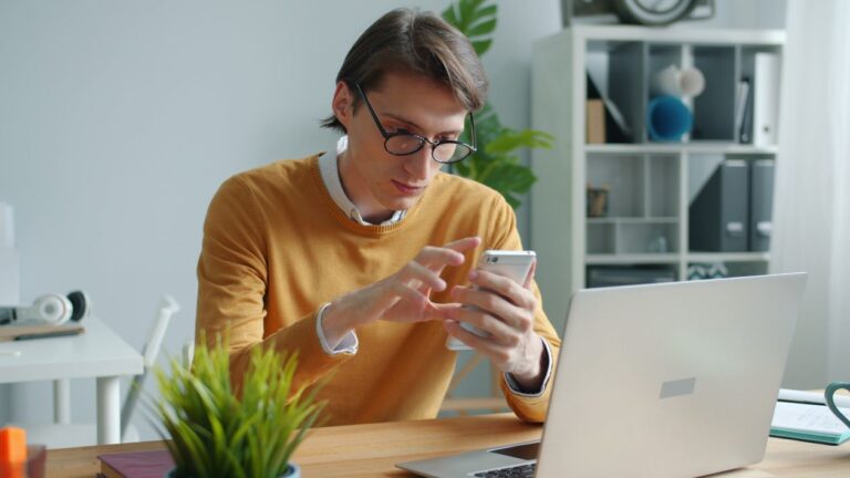 Concepto 013943 del 11-08-2026. RENTA PES. 7 Joven usa su celular frente a un computador portátil