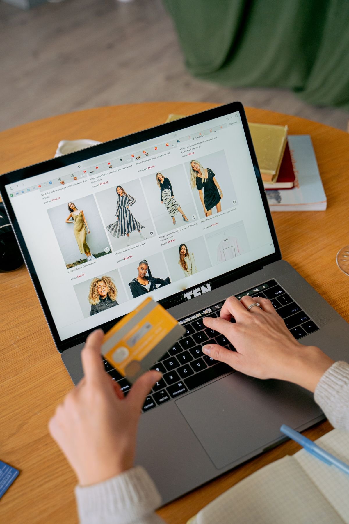 Mujer realiza una compra en línea con tarjeta de crédito desde su computador portátil en una tienda de ropa