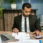 Hombre de traje trabaja con calculadora y documentos en una oficina