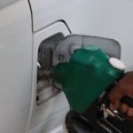 Mano llenando el tanque de un vehículo con la boquilla de un surtidor de gasolina