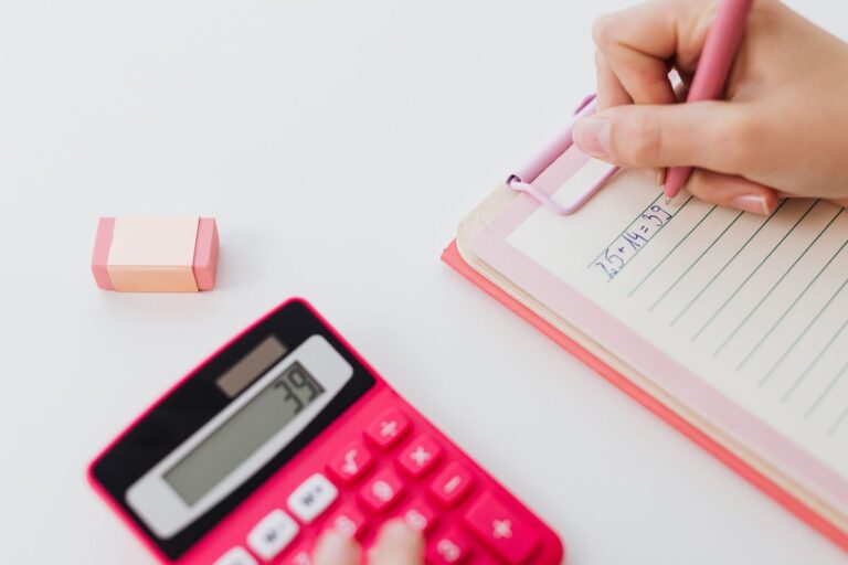 Persona escribiendo en un papel junto a una calculadora