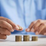 Manos apilando monedas doradas sobre una mesa