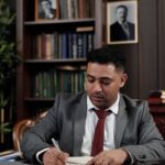 Profesional en traje firma un documento en su escritorio de oficina