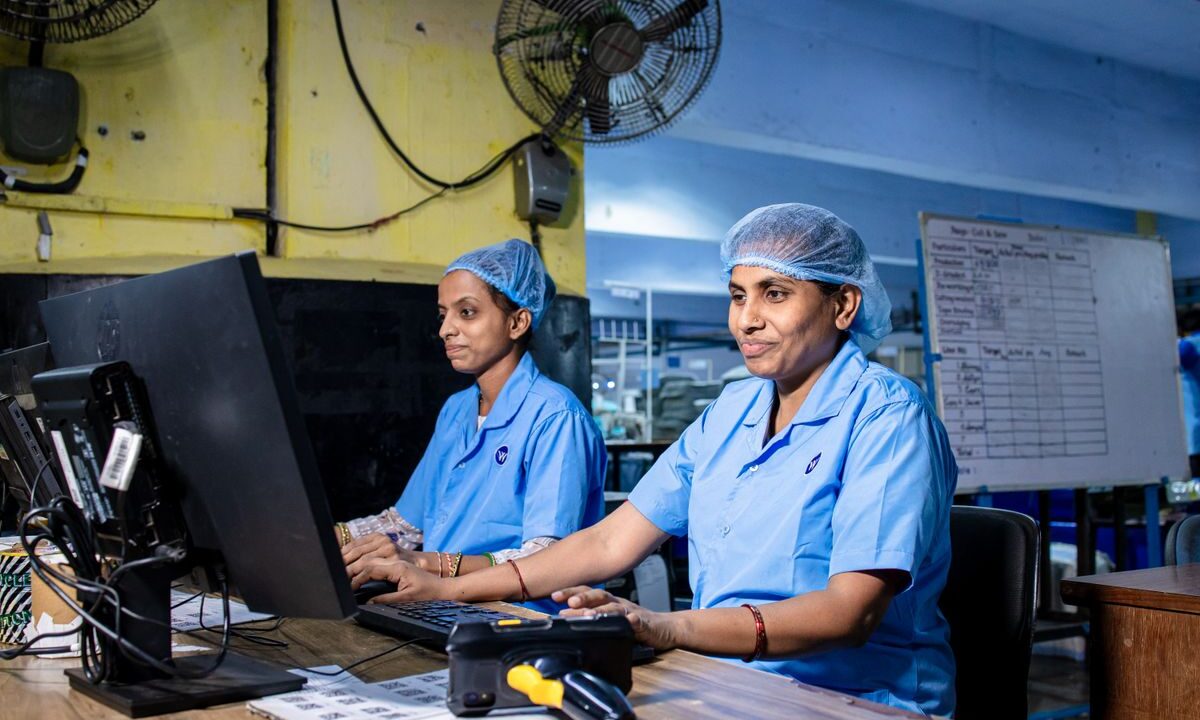 Trabajadoras con uniforme azul en los escritorios de una planta industrial