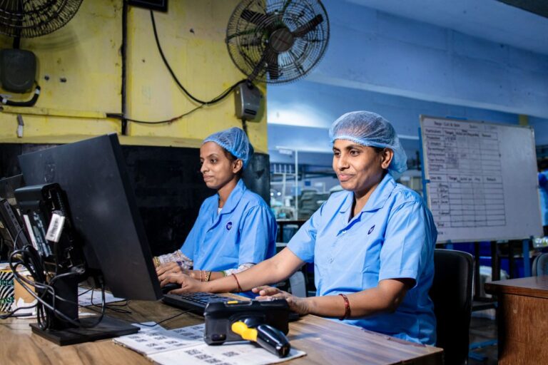 Trabajadoras con uniforme azul en los escritorios de una planta industrial