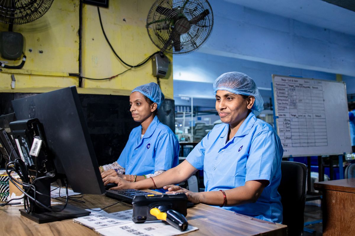 Trabajadoras con uniforme azul en los escritorios de una planta industrial