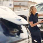 Concepto 018050 del 25-09-2026. Impuesto nacional al consumo. Vehículos híbridos frente a la exclusión de los vehículos eléctricos. Mujer carga un vehículo eléctrico en una estación de la ciudad