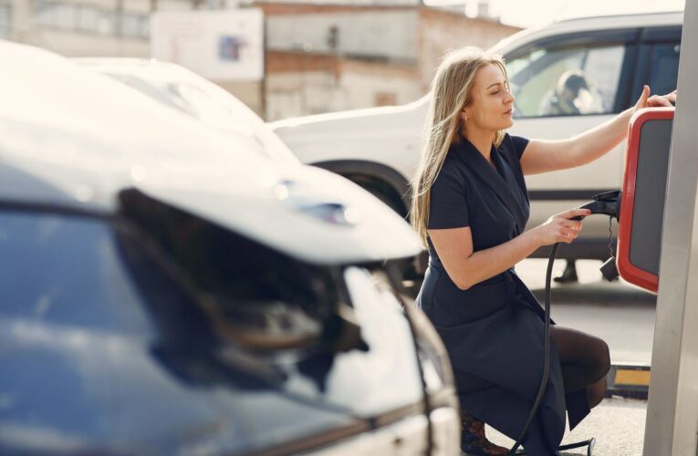 Concepto 018050 del 25-09-2026. Impuesto nacional al consumo. Vehículos híbridos frente a la exclusión de los vehículos eléctricos. 17 Mujer carga un vehículo eléctrico en una estación de la ciudad