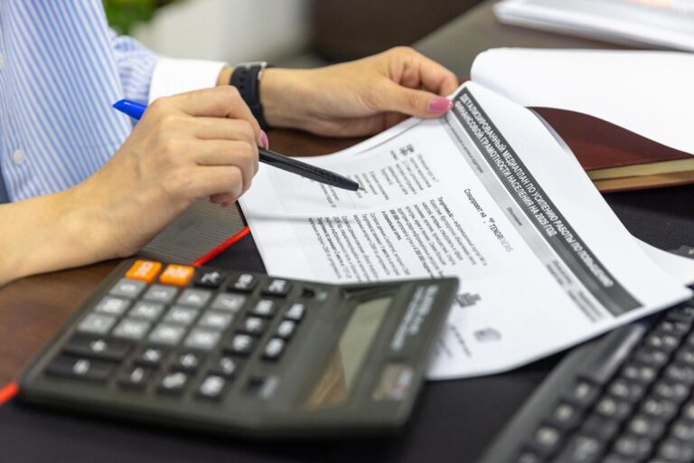 Persona revisando documentos financieros con una calculadora y un bolígrafo