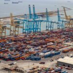 Vista aérea de un puerto con contenedores apilados y grúas de carga