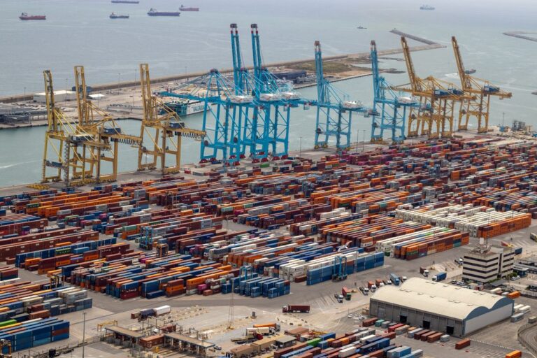 Vista aérea de un puerto con contenedores apilados y grúas de carga