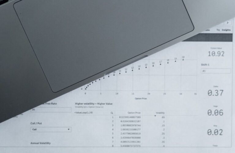 Vista superior de hojas de reportes con datos y un computador portátil en una oficina