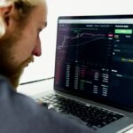 Hombre analiza datos de inversiones en la pantalla de su computador