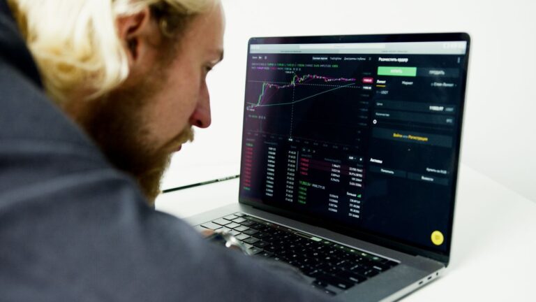 Hombre analiza datos de inversiones en la pantalla de su computador