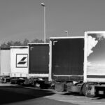 Fila de tractocamiones estacionados en una zona de cargue, en blanco y negro