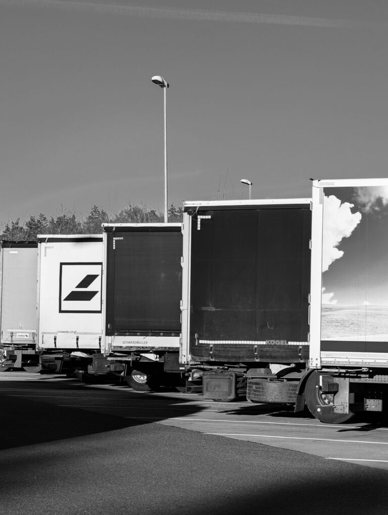 Fila de tractocamiones estacionados en una zona de cargue, en blanco y negro