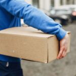 Mensajero que carga un paquete de cartón para su entrega