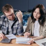 La Ley de Rescate subiría a 95.500 UVT el umbral del impuesto al patrimonio entre 2027 y 2030 Pareja revisando cuentas del hogar con una calculadora y un portátil