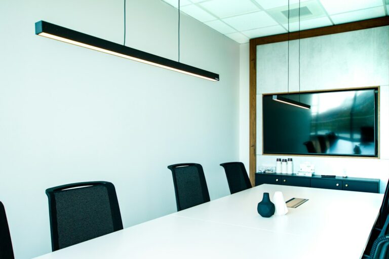 Sala de juntas con mesa blanca y sillas negras